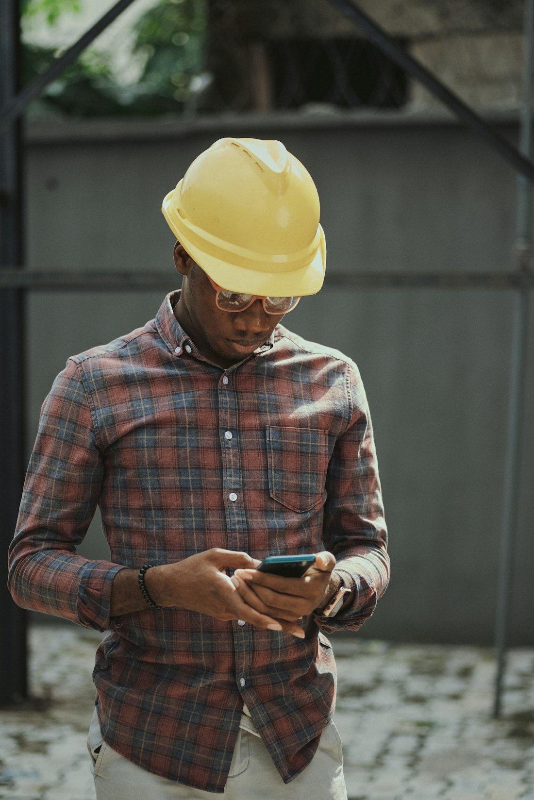 A technician in a hard hat using a smartphone on site
